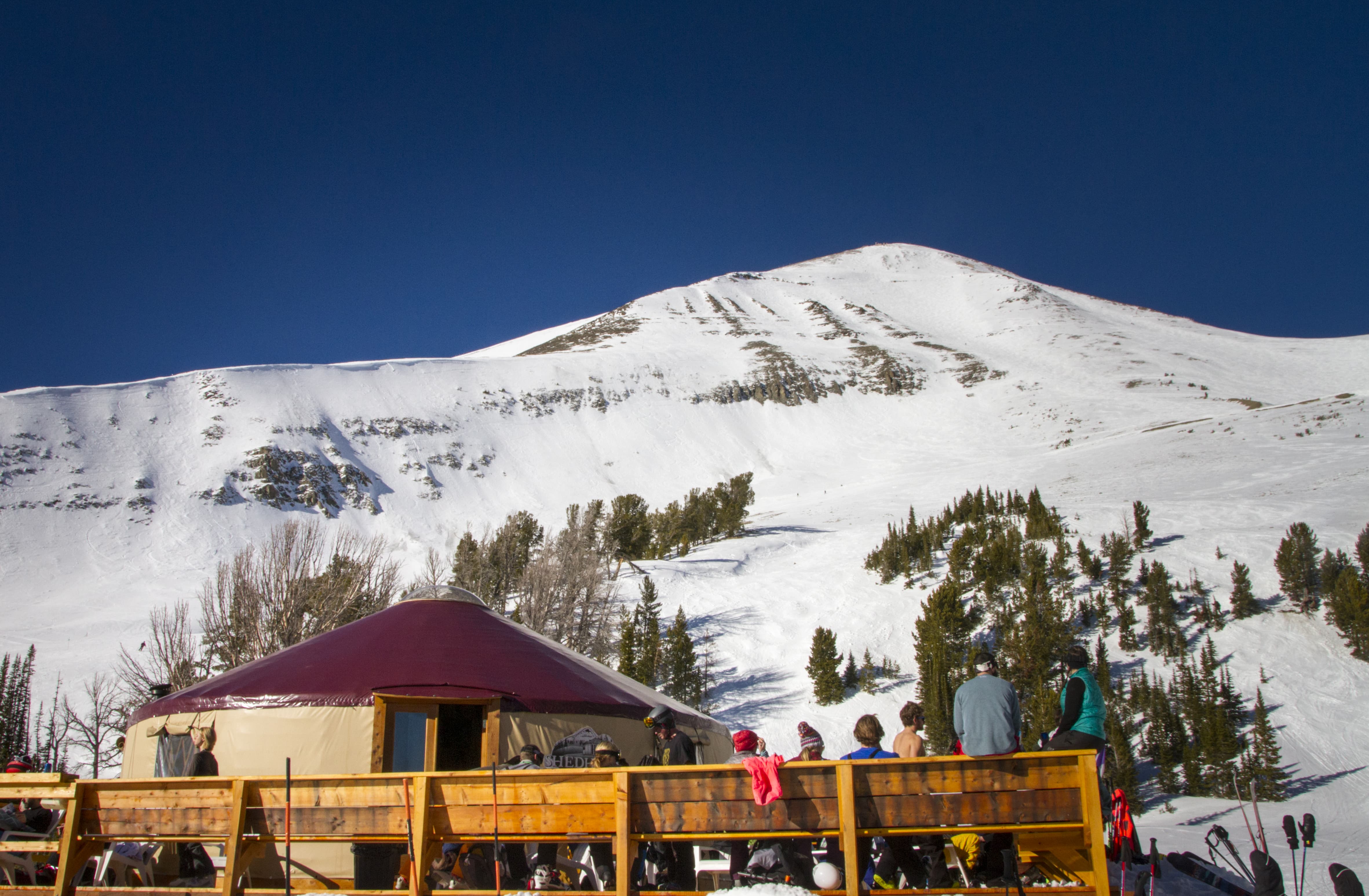 tan yurt with red roof in big sky montana with a mountain in the background