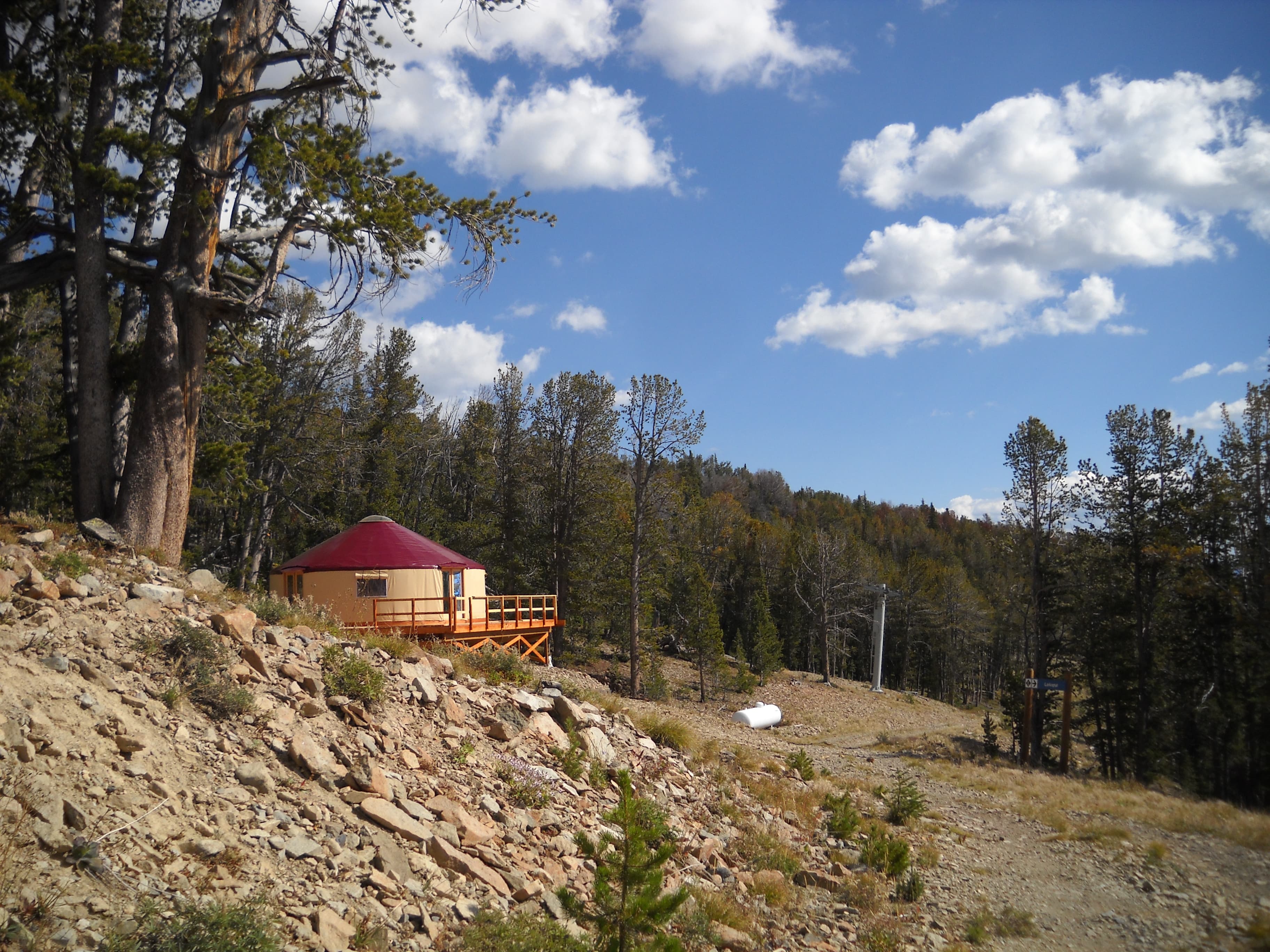 tan yurt with a red roof in the montana forest