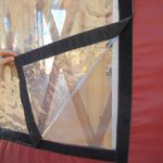 person lifting up the corner of a vinyl yurt window