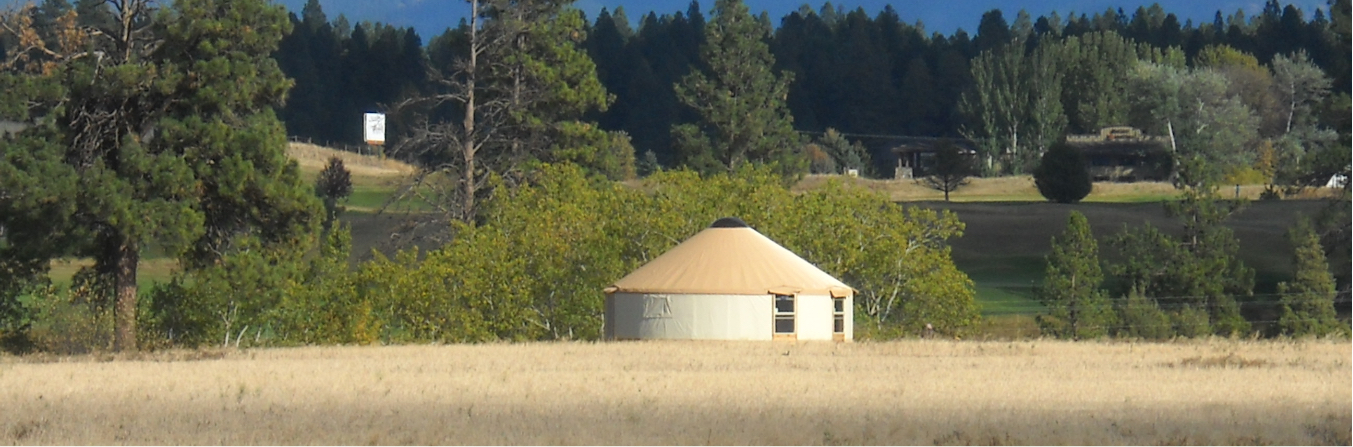 white and tan yurt in a field