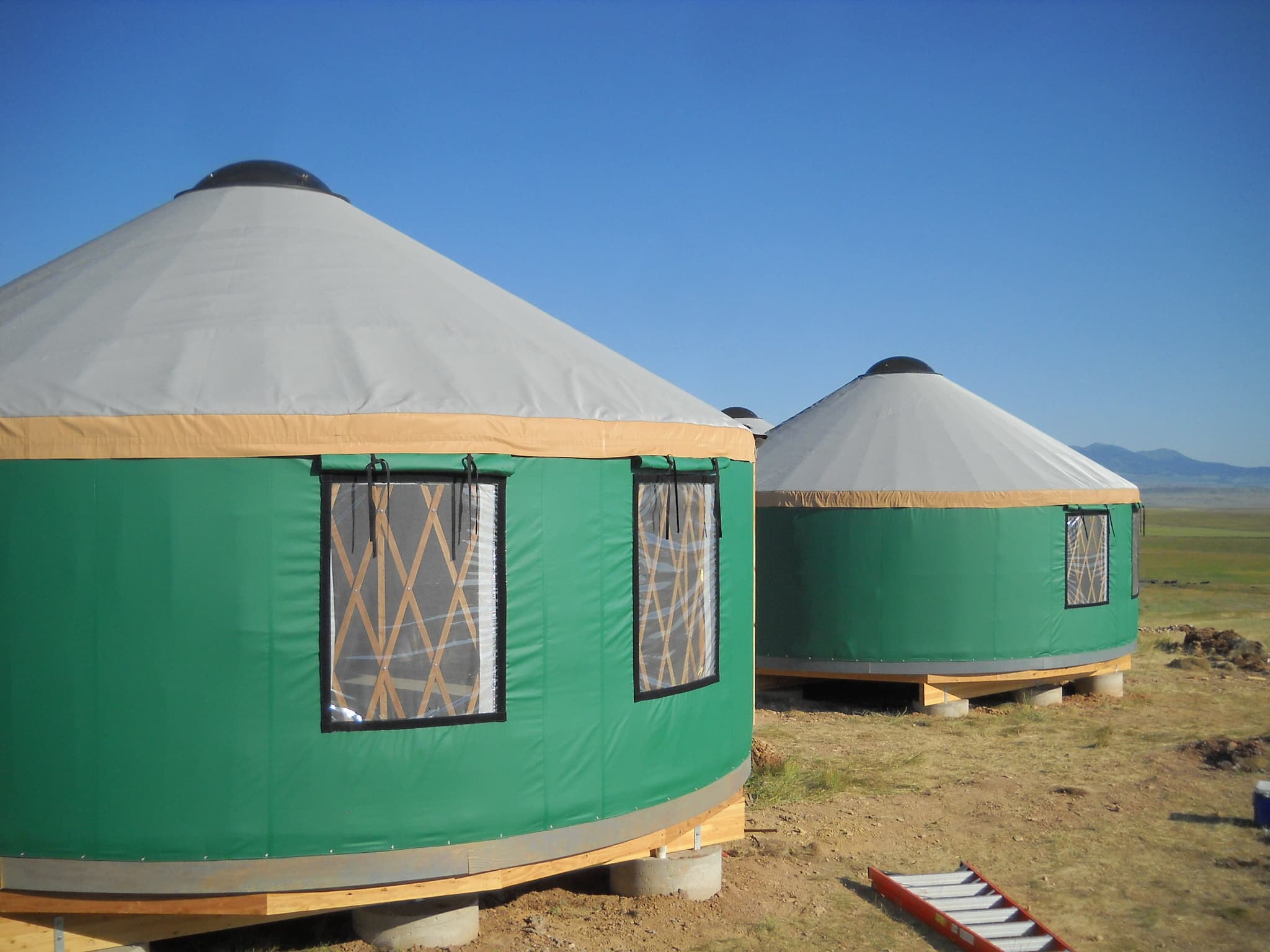 two green yurts with grey roofs