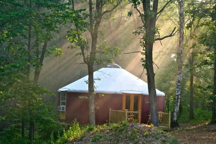 red yurt with a white roof in the forest