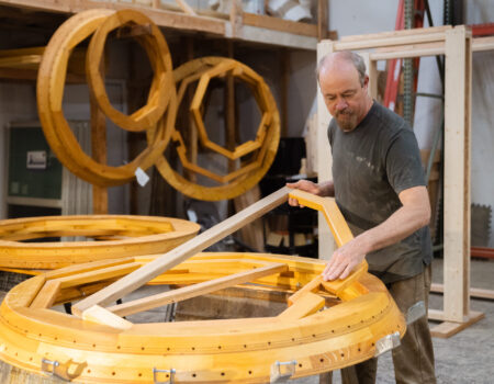 a man holding a piece of wood standing above a part of yurt