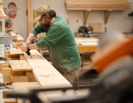 a man drills out a board in a wood shop