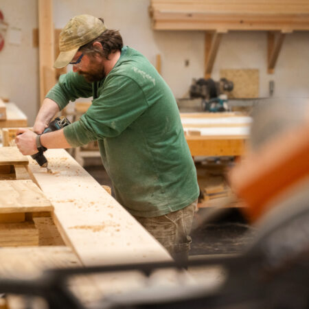 a man drills out a board in a wood shop