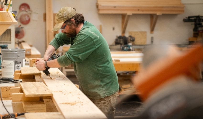 handmade yurt company a man working on a piece of wood with a drill